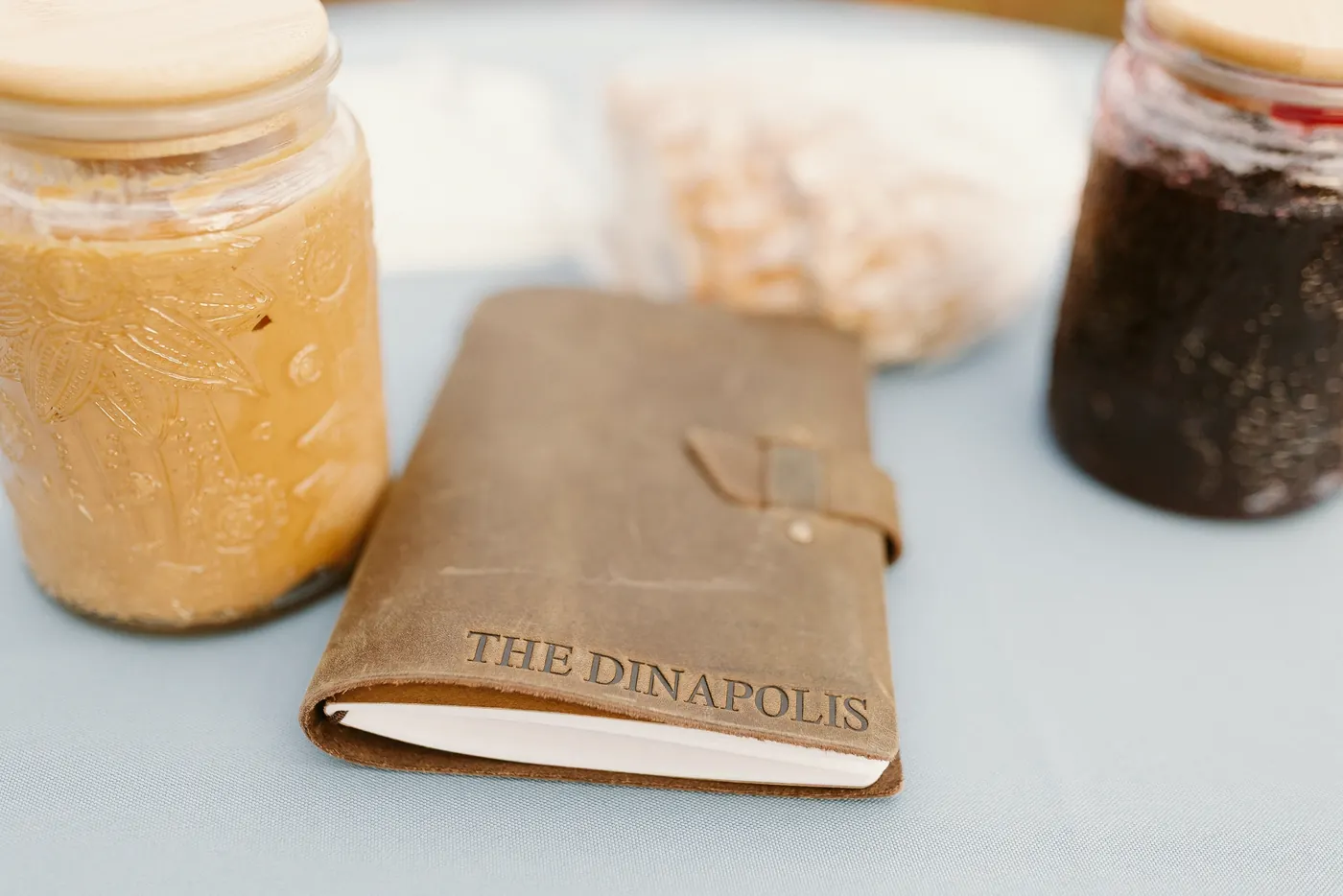Jars of peanut butter and jelly beside an engraved leather vow book on the ceremony table