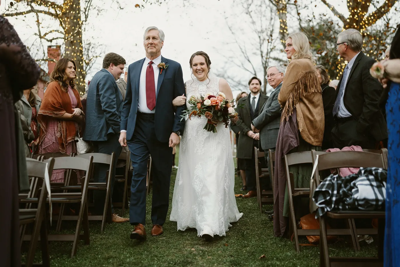 Kelsey's dad walking her down the aisle past smiling guests