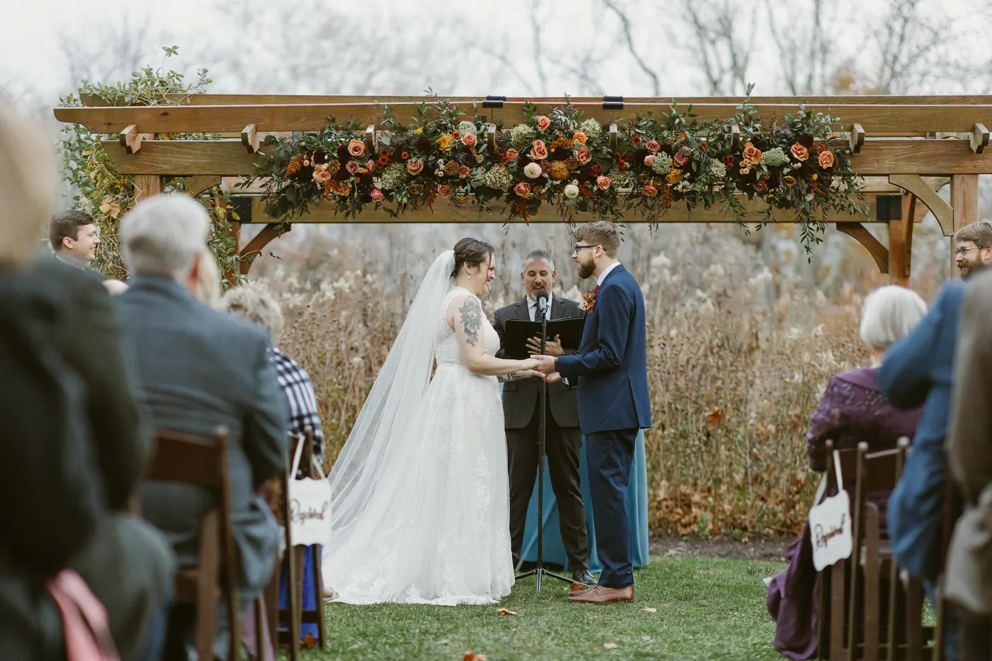 Guests watching Jimmy and Kelsey's ceremony beneath the flower-covered pergola