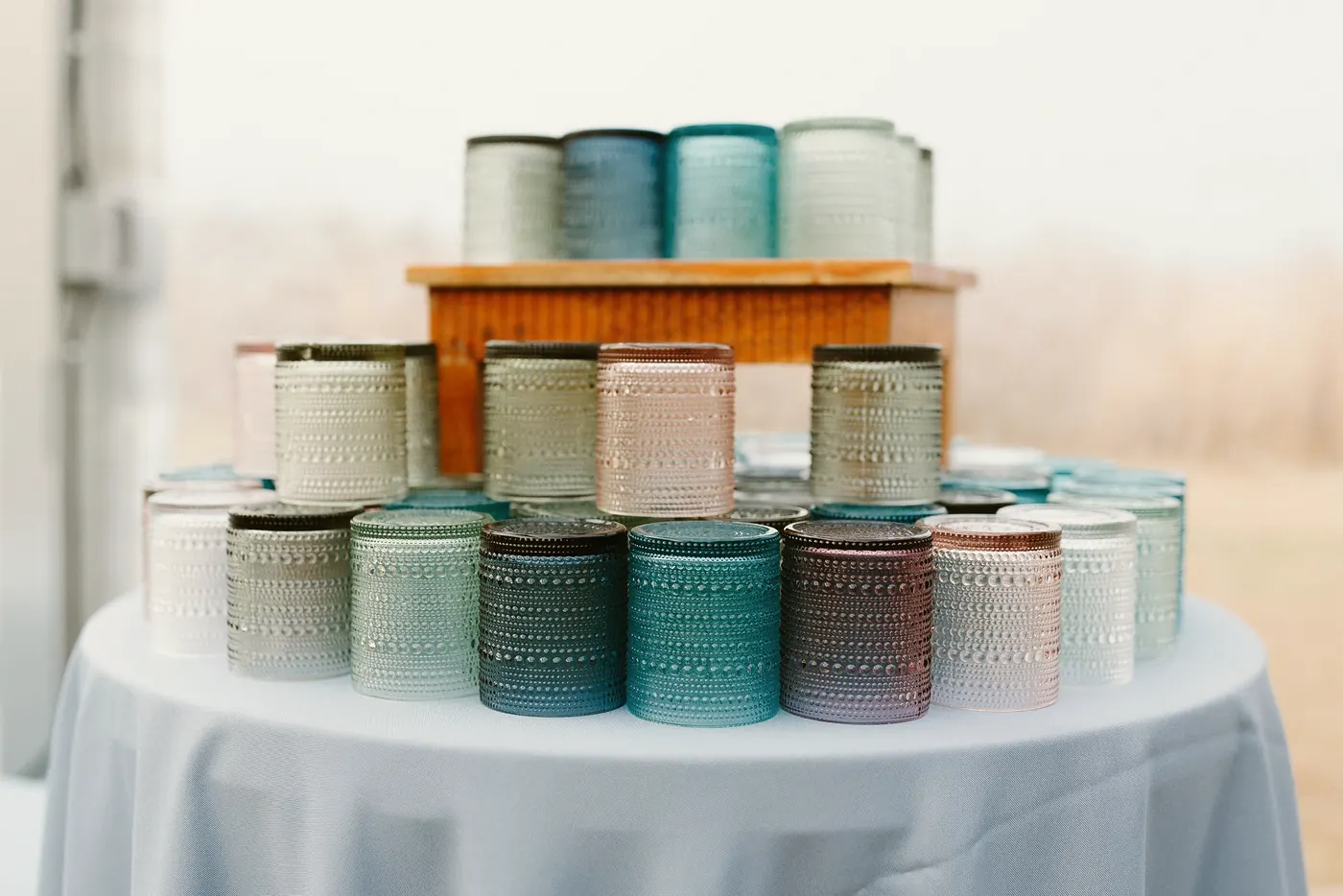 Colorful glass candle holders stacked on a table at the reception