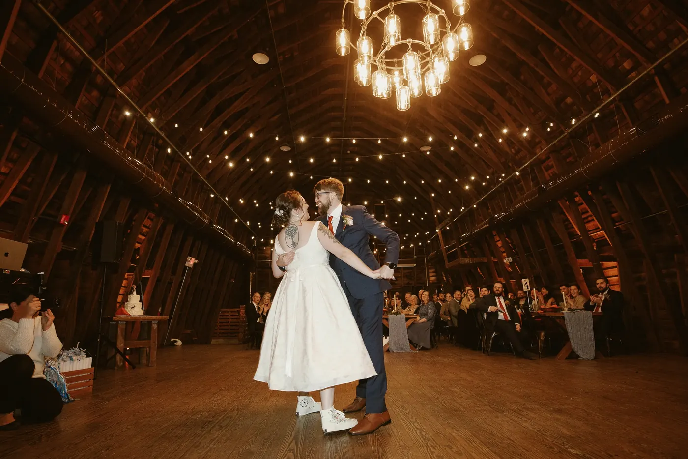 Jimmy and Kelsey's first dance under the chandelier and string lights in the barn
