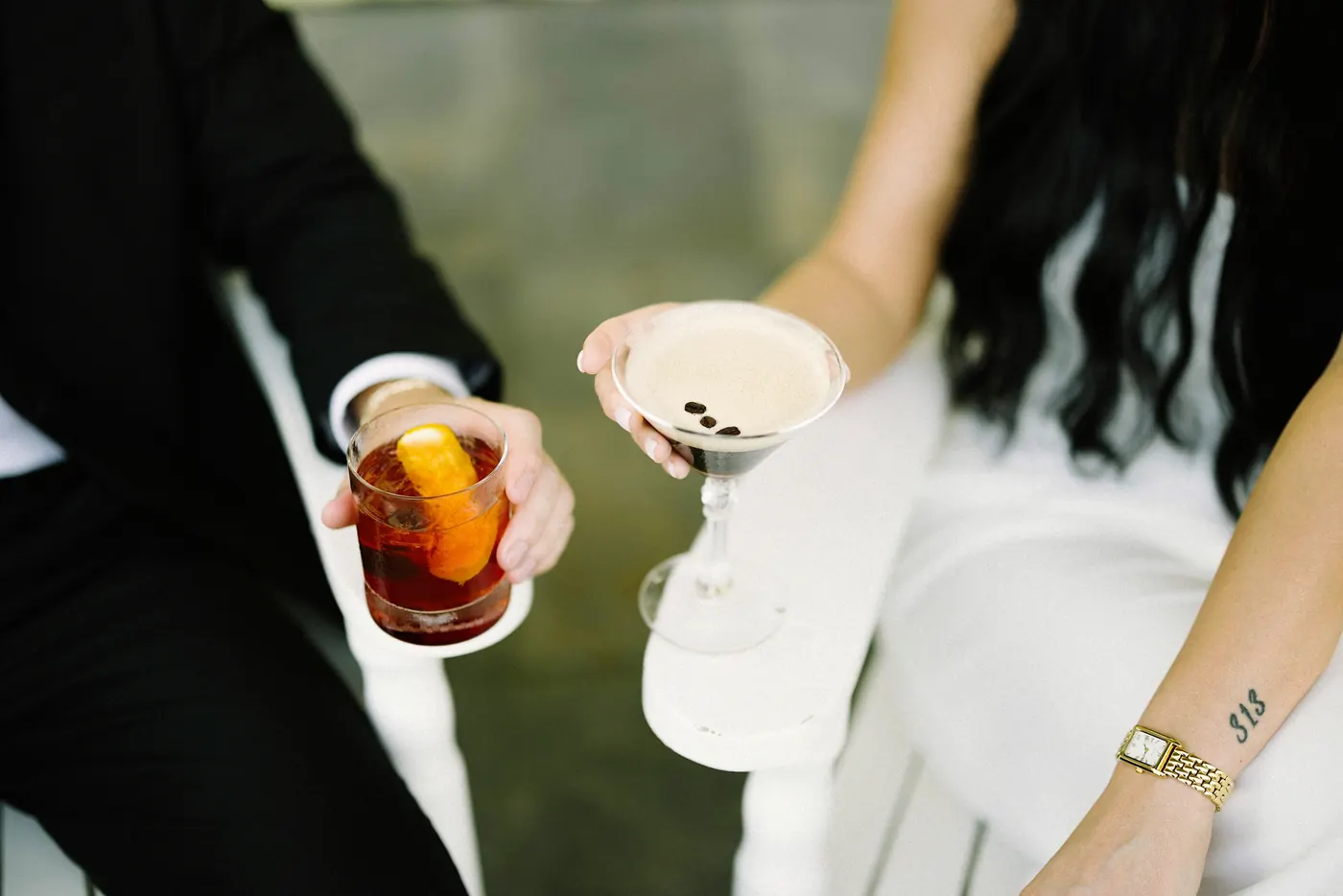 Mason and Morgan holding an old fashioned and an espresso martini on the porch of Congress Hall in Cape May, NJ