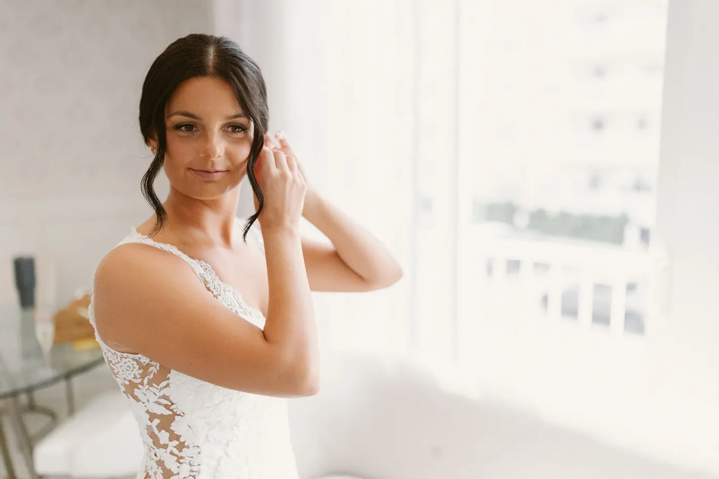 Morgan putting on her earrings by the window at ICONA Diamond Beach