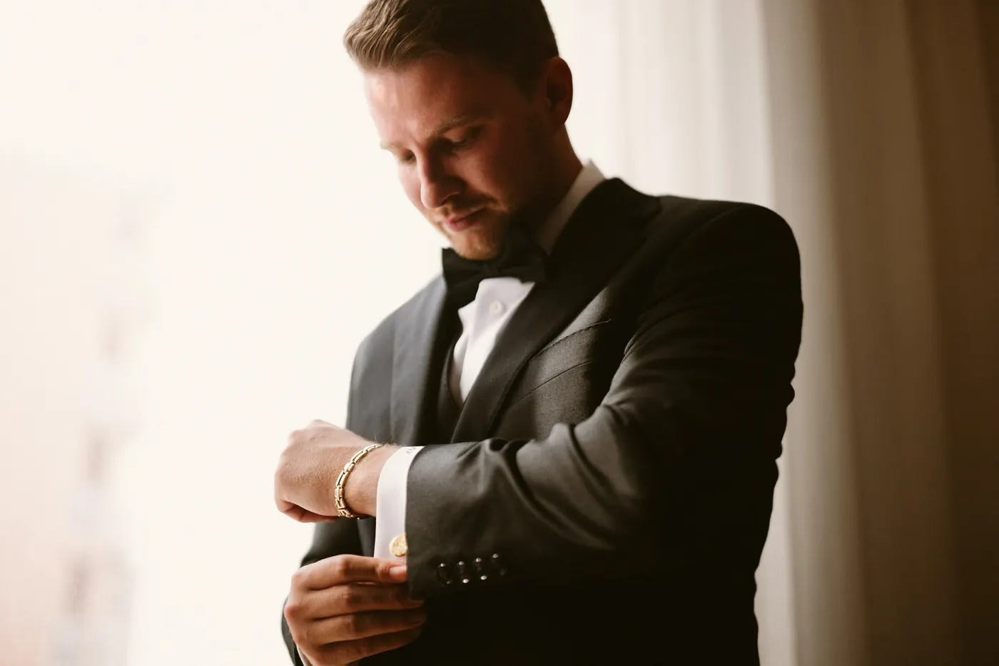 Mason fastening his cufflinks by the window
