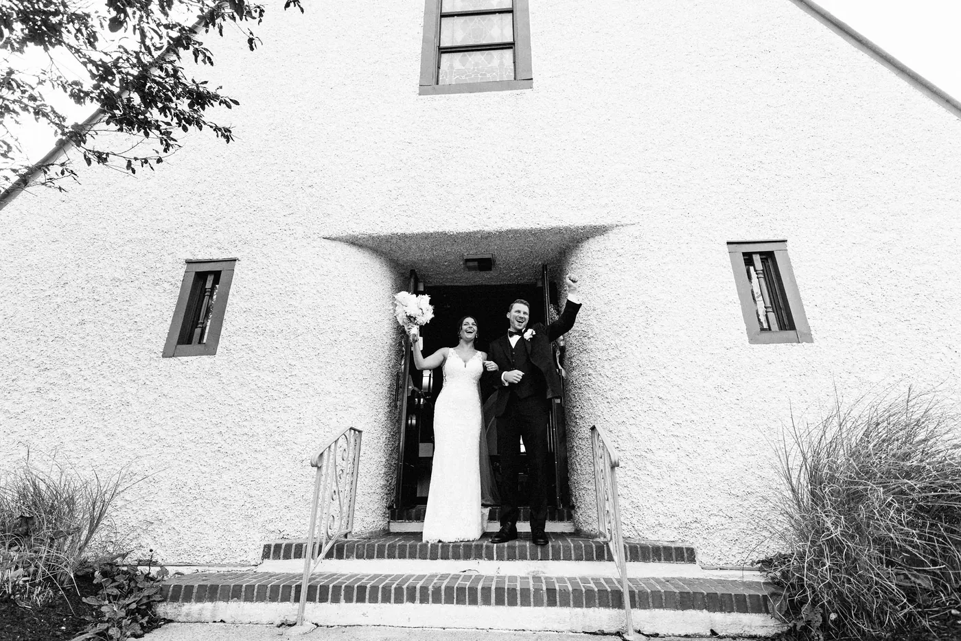 Black and white photo of Mason and Morgan cheering in the doorway of Sacred Heart Church