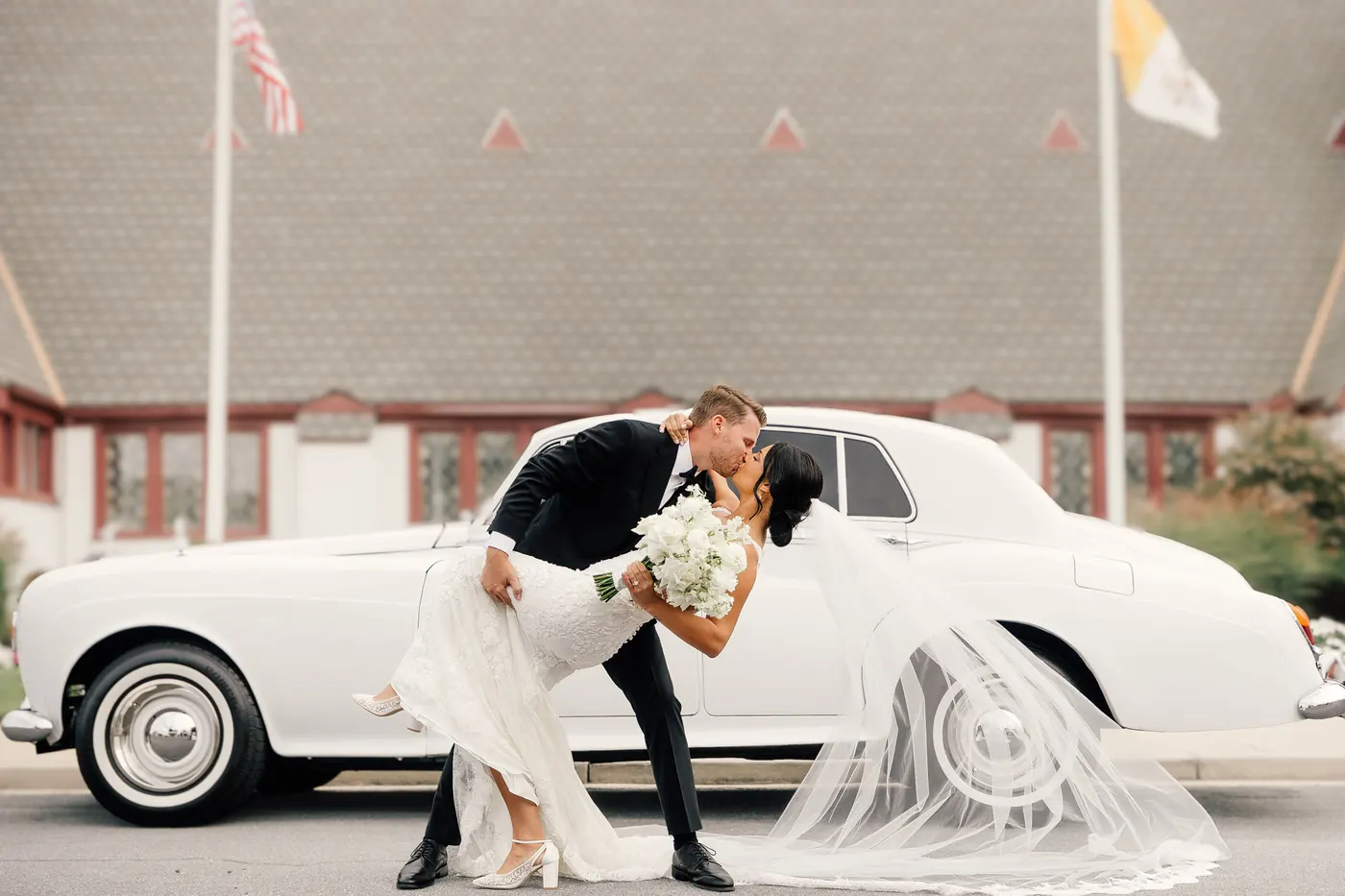 Mason dipping Morgan for a kiss beside the vintage Rolls-Royce in front of Sacred Heart Church