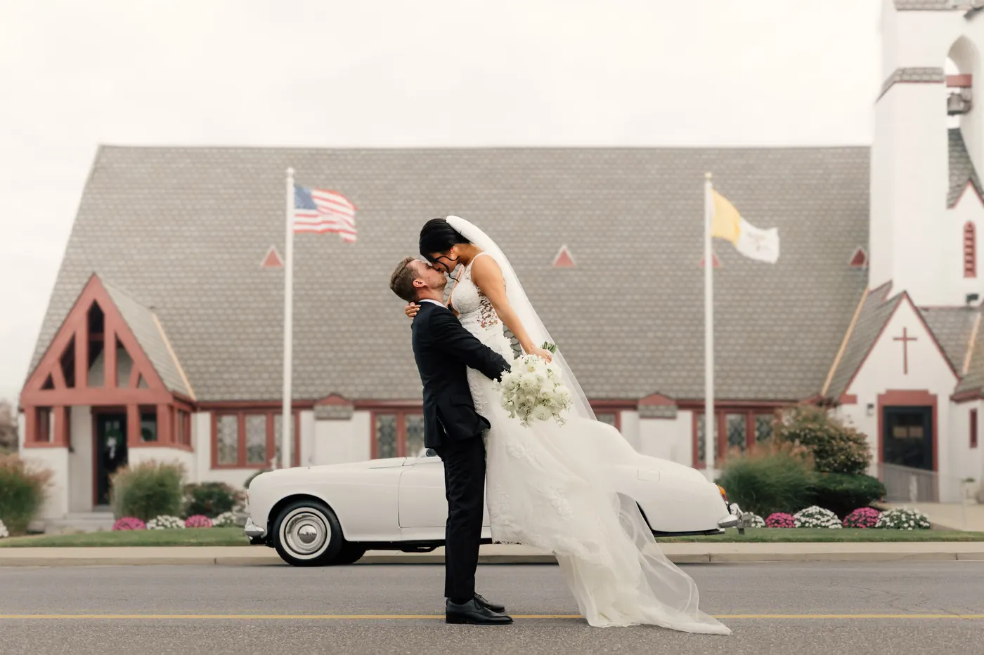 Mason lifting Morgan for a kiss in front of Sacred Heart Church in Avalon