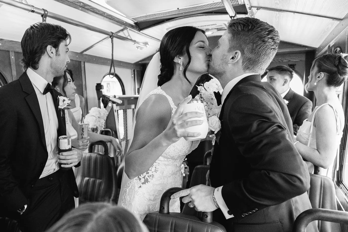 Black and white photo of Mason and Morgan kissing on the trolley with their wedding party