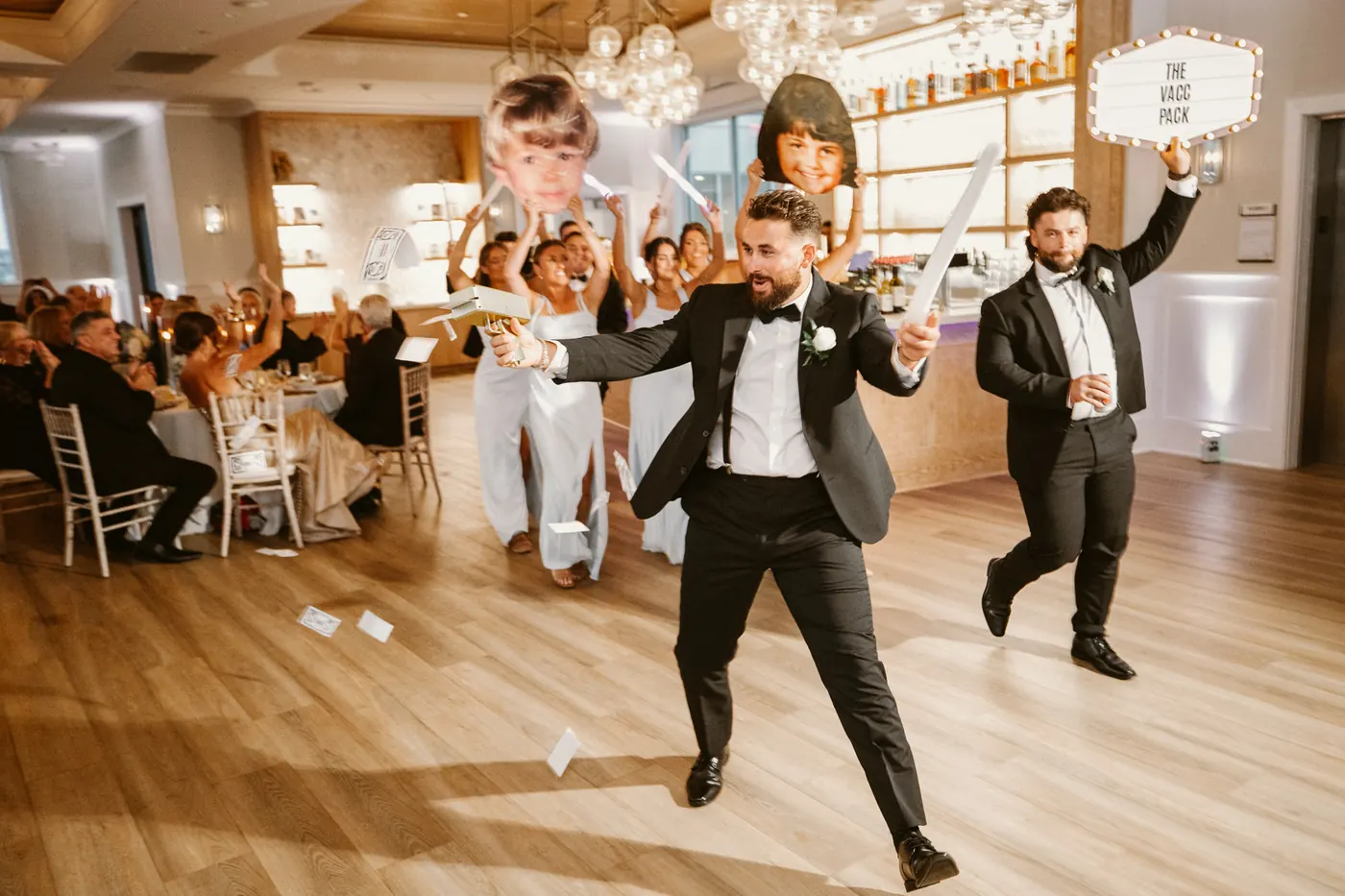 Groomsmen dancing into the reception holding giant face cutouts