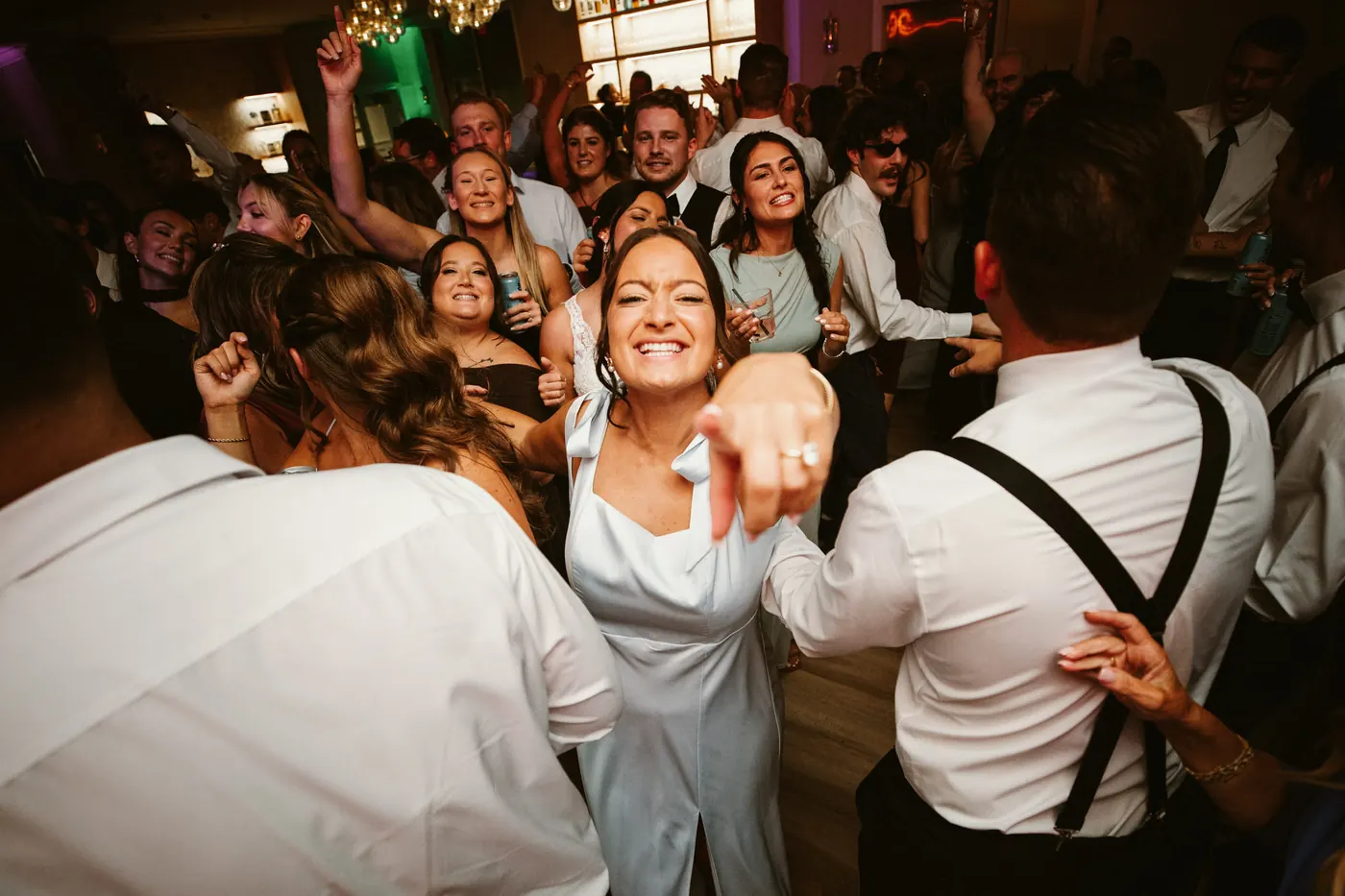 A bridesmaid pointing at the camera on a packed dance floor