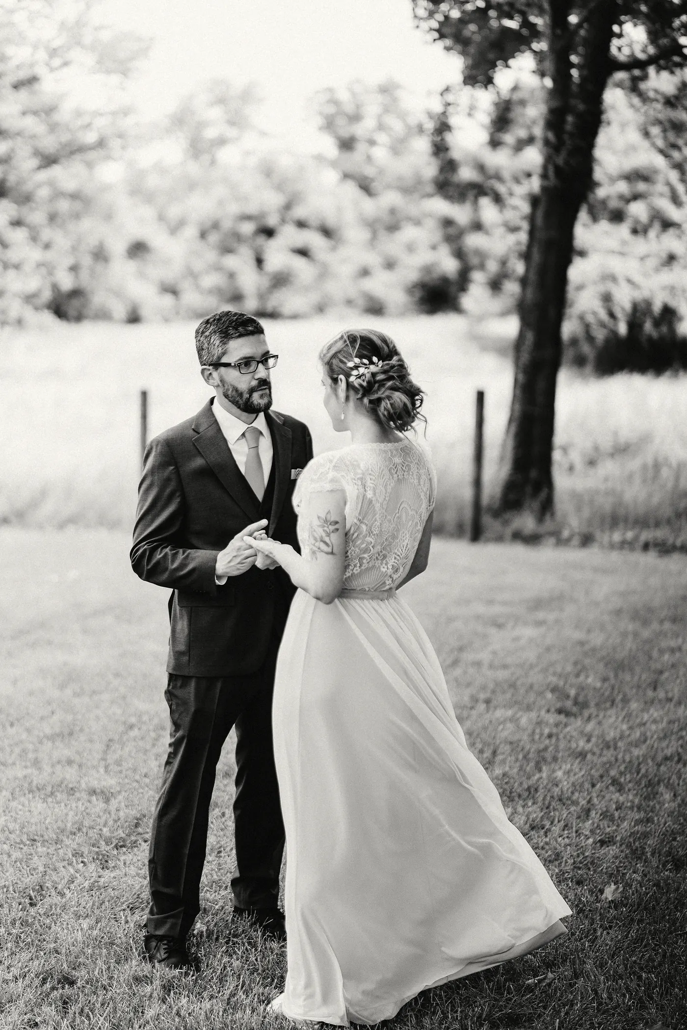Black and white photo of Matt and Erica holding hands on the lawn at Johnson's Locust Hall Farm in Jobstown, NJ
