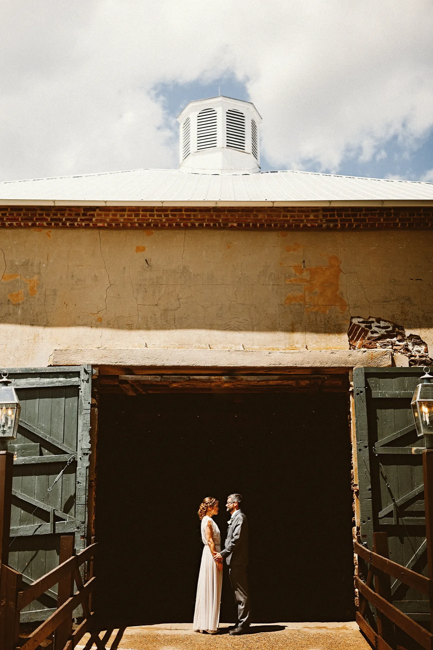 Matt and Erica holding hands in the big doorway of the barn at Johnson's Locust Hall Farm in Jobstown, NJ