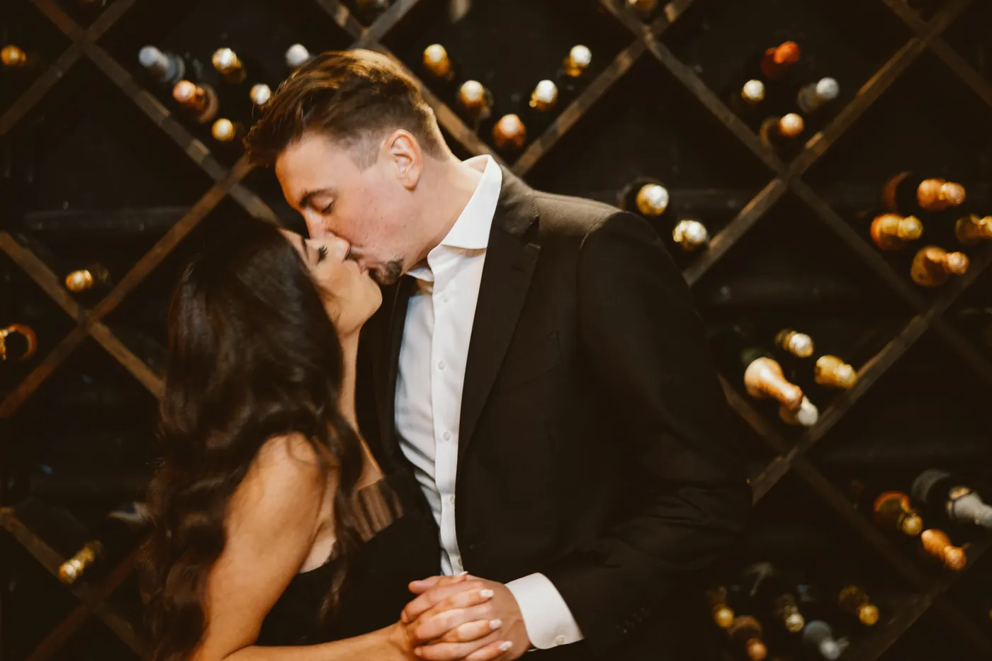 Morgan and Will kissing in front of the wine racks in the cellar at Renault Winery in Egg Harbor City, NJ