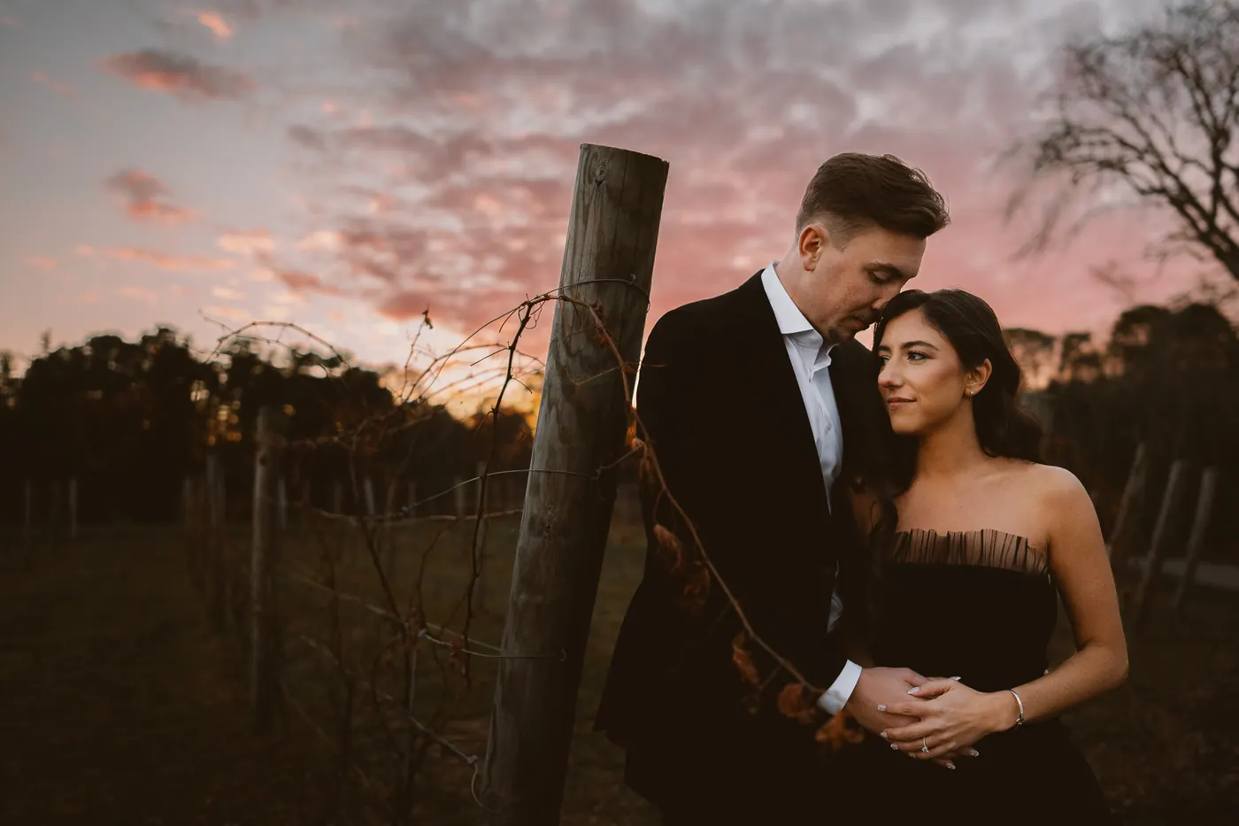 Morgan and Will by a vineyard post under a pink sunset sky at Renault Winery in Egg Harbor City, NJ
