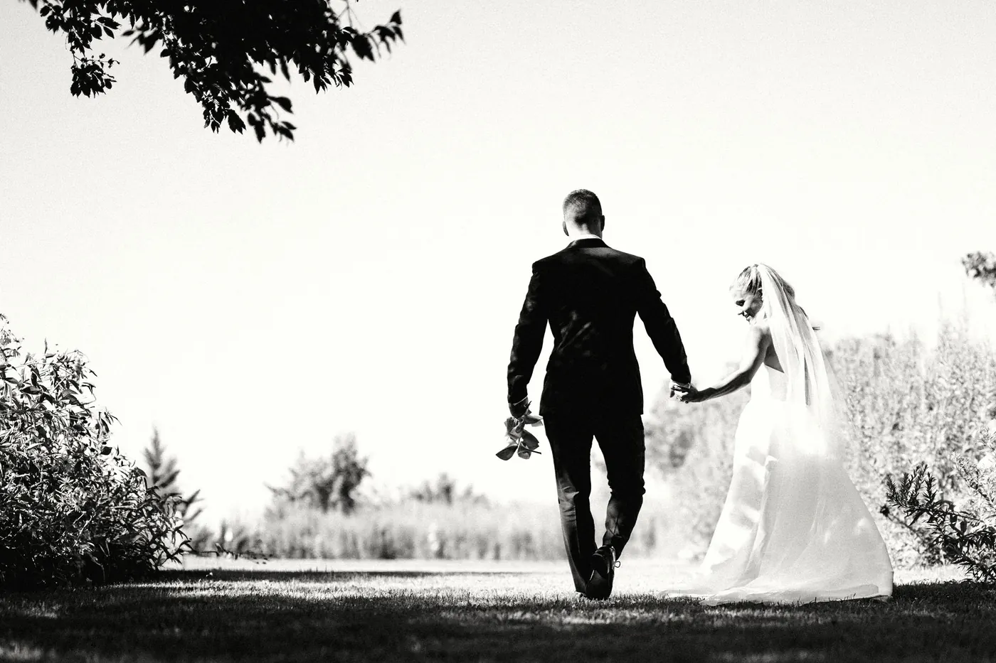 Steve and Madison walking hand in hand into the field, in black and white