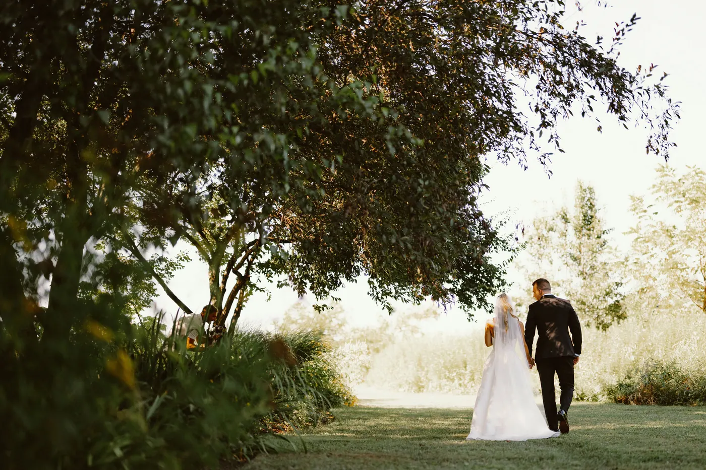 Steve and Madison walking across the lawn beneath a large tree