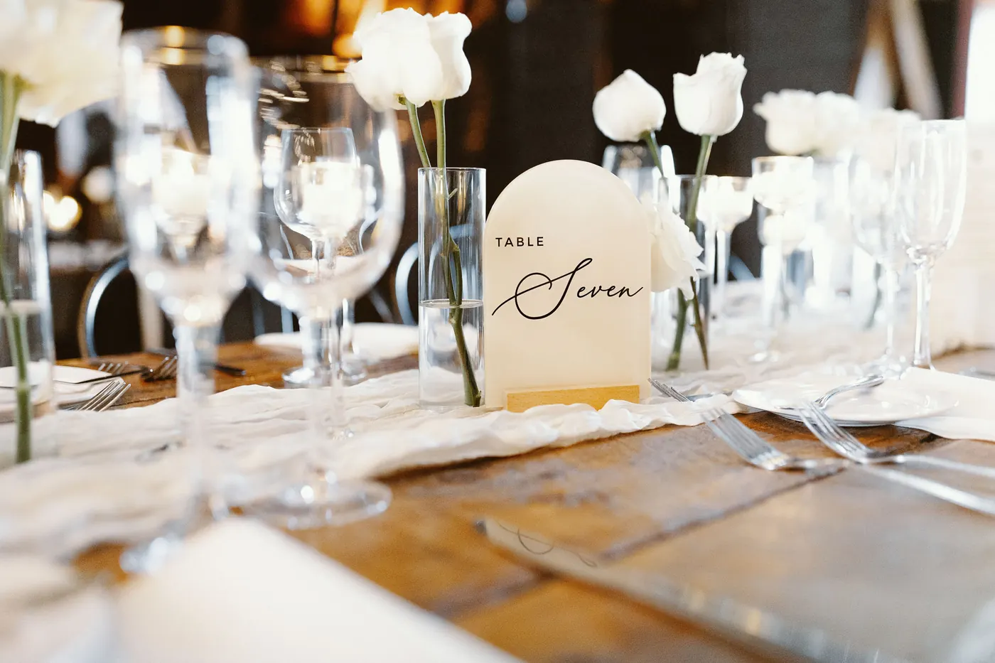 A calligraphy table number and white tulips on a reception table