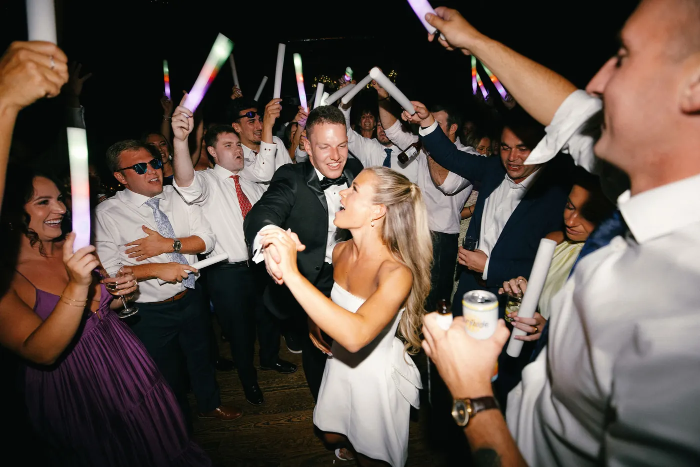 A packed dance floor full of guests and glowing light sticks