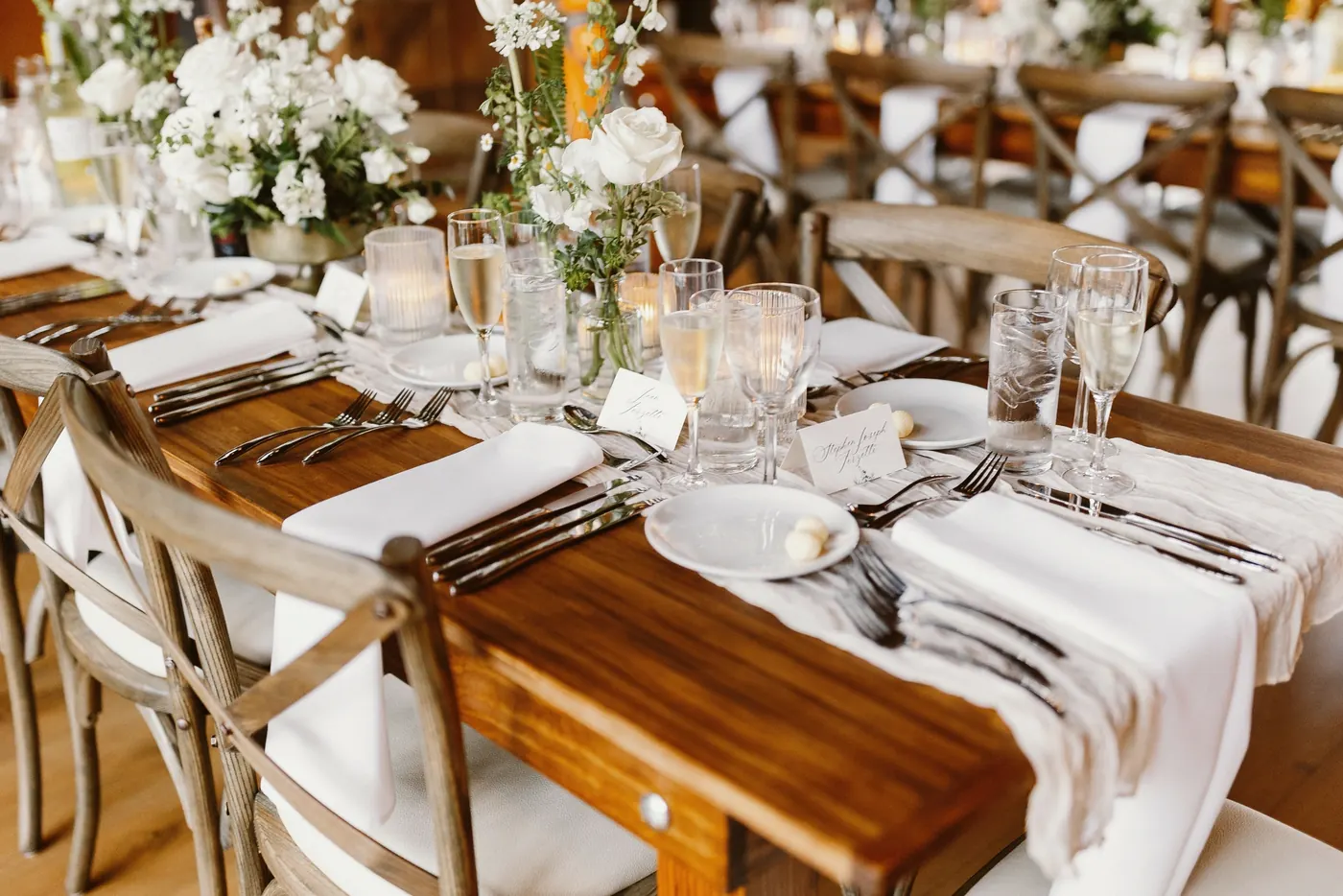 Reception tables set with white flowers, candles and wooden cross-back chairs